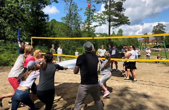 Folk som kaster vannballong over volleyball-nett
